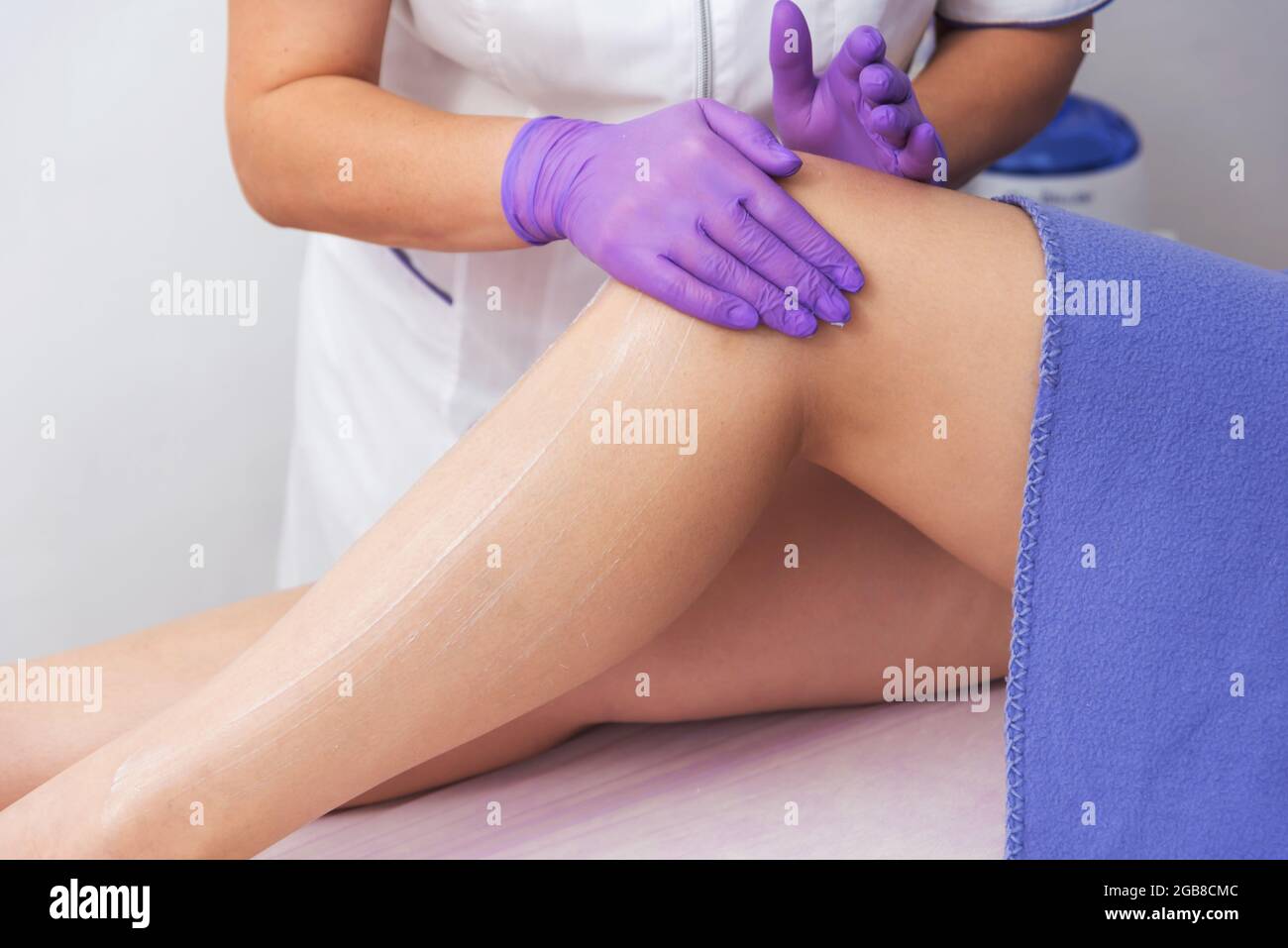 Kosmetisches Verfahren Anwendung von Creme auf die Beine Enthaarung Epilation Reibecreme Hautaufweichung Stockfoto