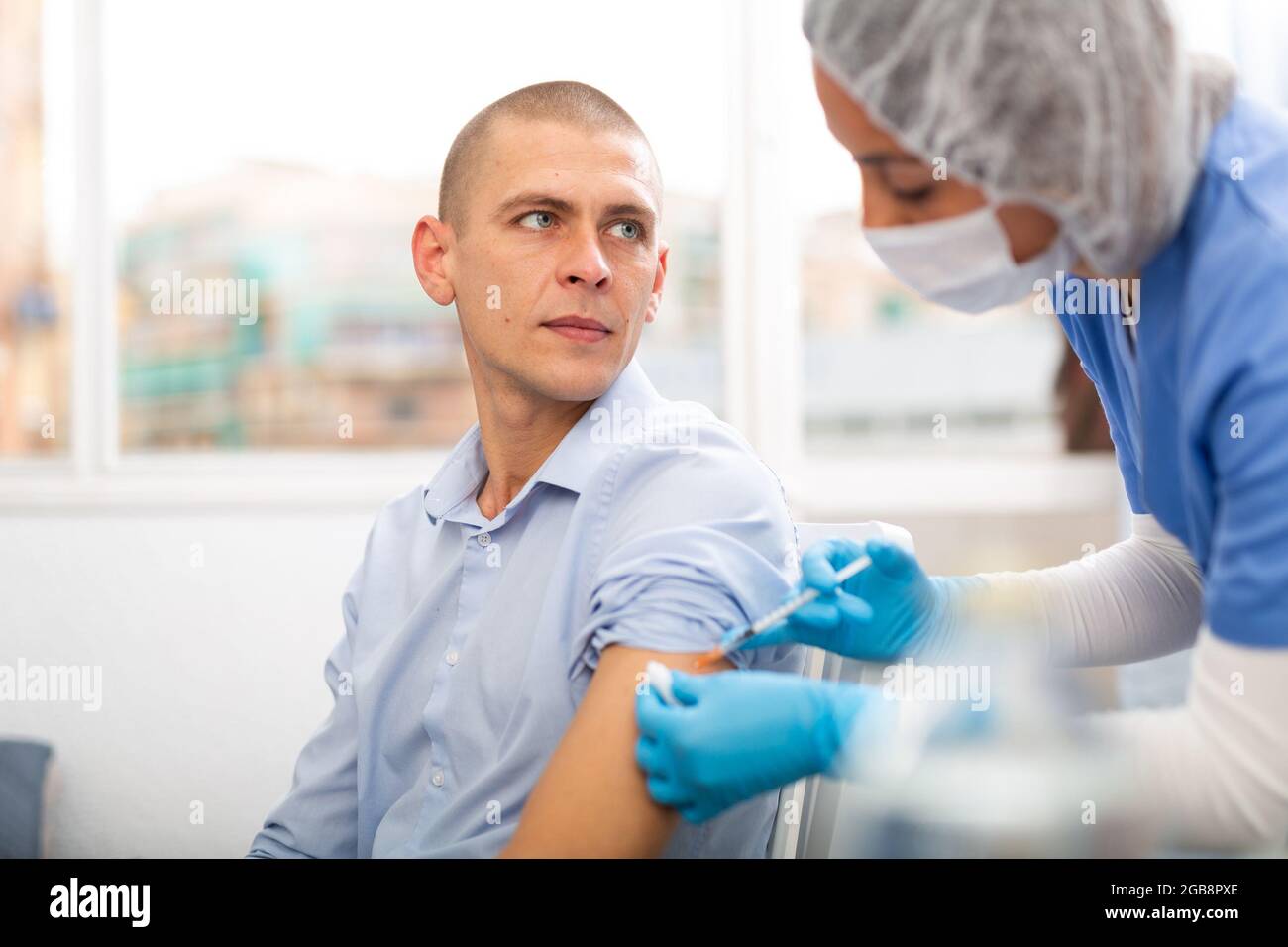 Arzt in einer schützenden Gesichtsmaske macht Impfung Stockfoto