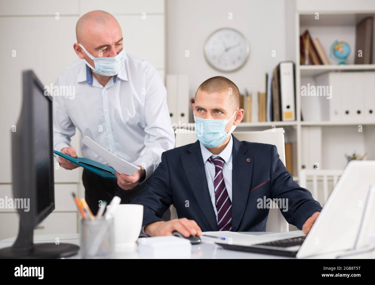 Zwei Geschäftsleute in Fase Masken diskutieren neue Ideen Stockfoto