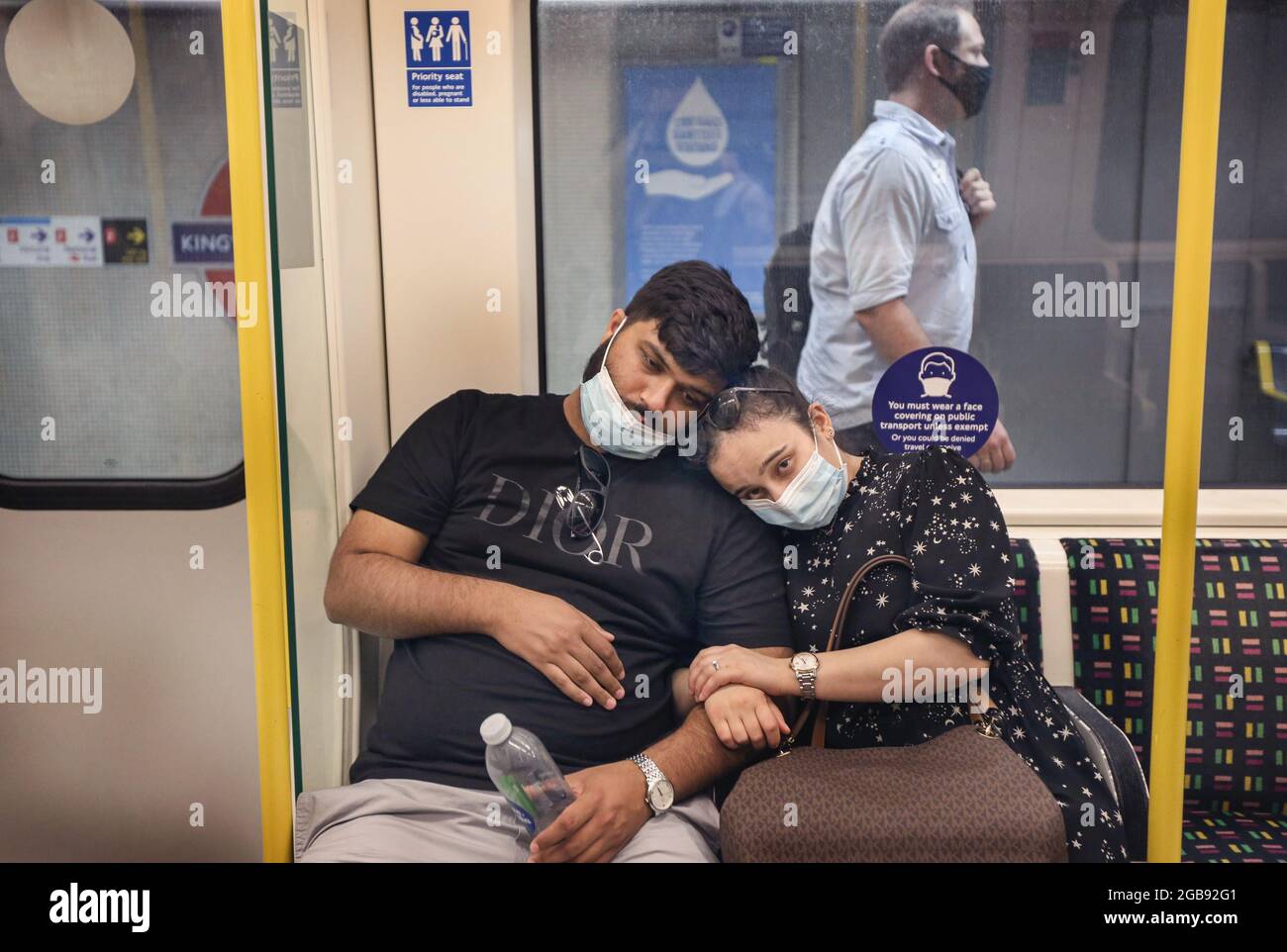 London, Großbritannien. Juli 2021. Ein Paar sah Gesichtsmasken tragen, als sie an der Kings Cross Station ankamen. Trotz des Endes der gesetzlichen Pflicht zum Tragen von Gesichtsmasken in England ist das Tragen von Gesichtsmasken auf Londoner Transportmitteln weiterhin obligatorisch und die Menschen halten sich weiterhin an die Vorschriften. Kredit: SOPA Images Limited/Alamy Live Nachrichten Stockfoto