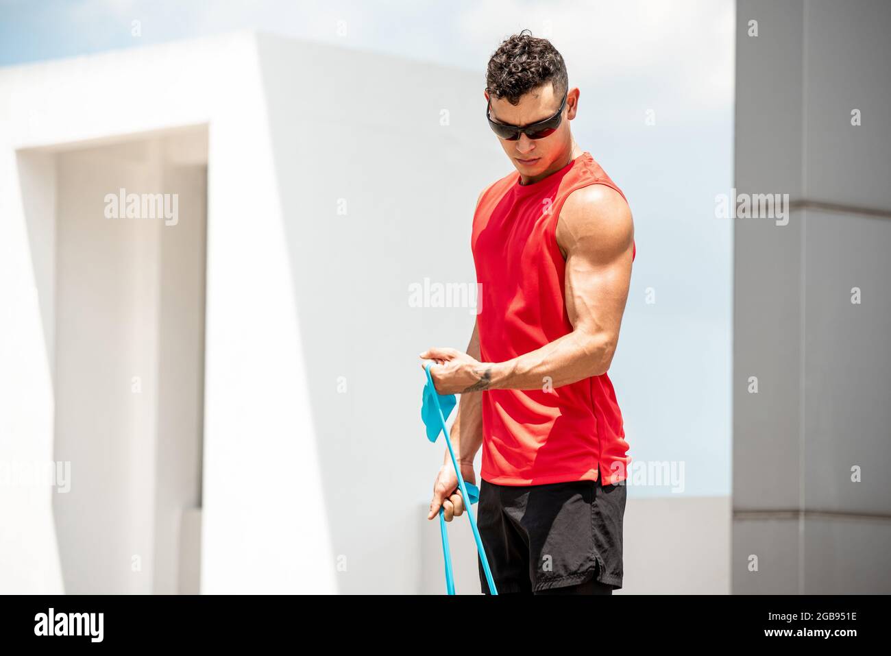 Gut aussehend gesund fit Sport Mann tun Bicep Curl Übung mit elastischen Widerstandsband im Freien - Home Open Air Workout Konzept Stockfoto