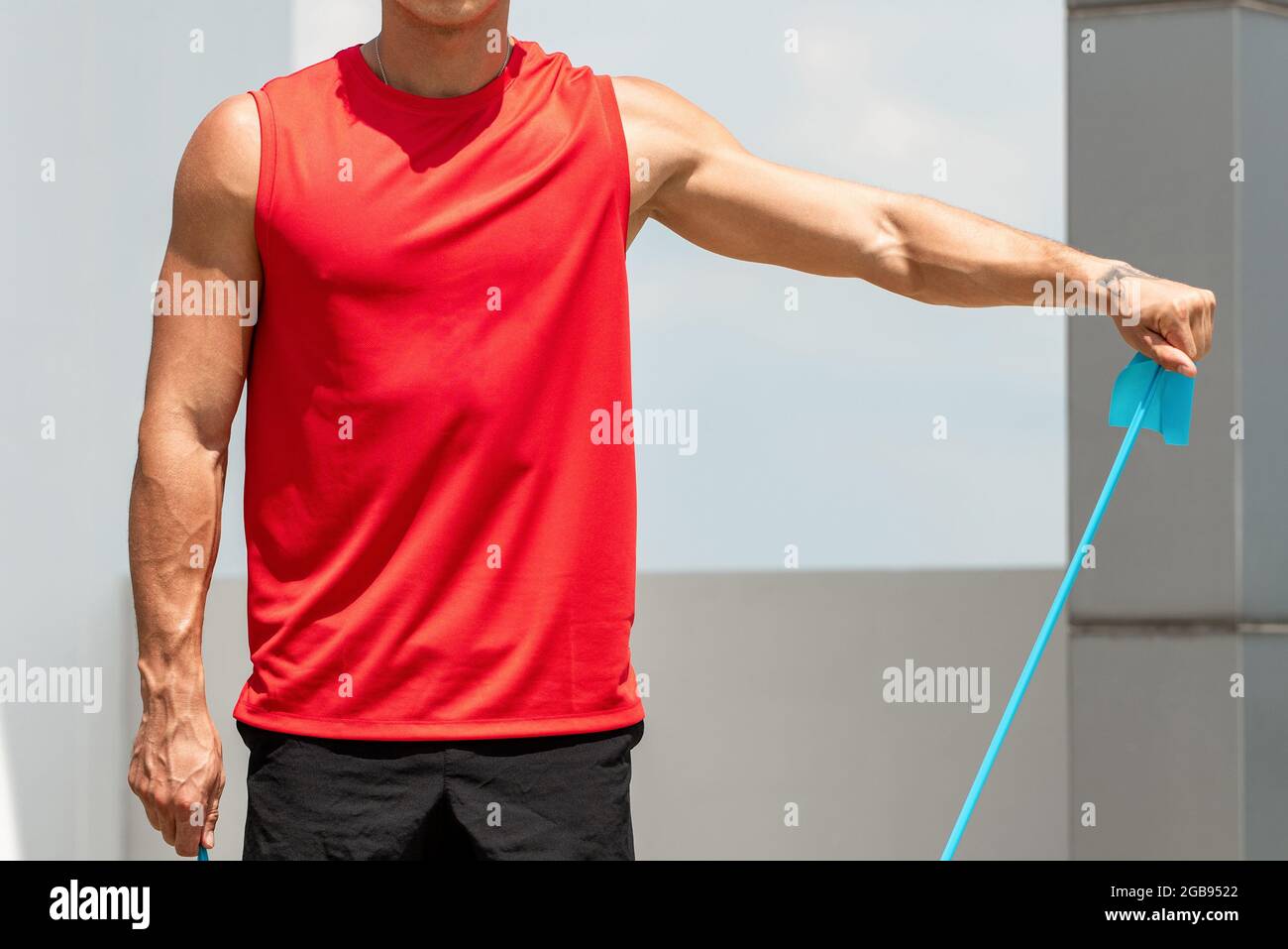 Junge fit Mann tut Schulter lateral erhöhen trainieren mit Widerstandsband zu Hause im Freien Stockfoto
