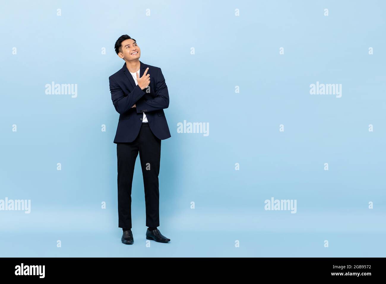 In voller Länge Porträt von jungen schönen südöstlichen asiatischen Geschäftsmann suchen und zeigen, um Raum auf hellblauen Studio-Hintergrund kopieren Stockfoto