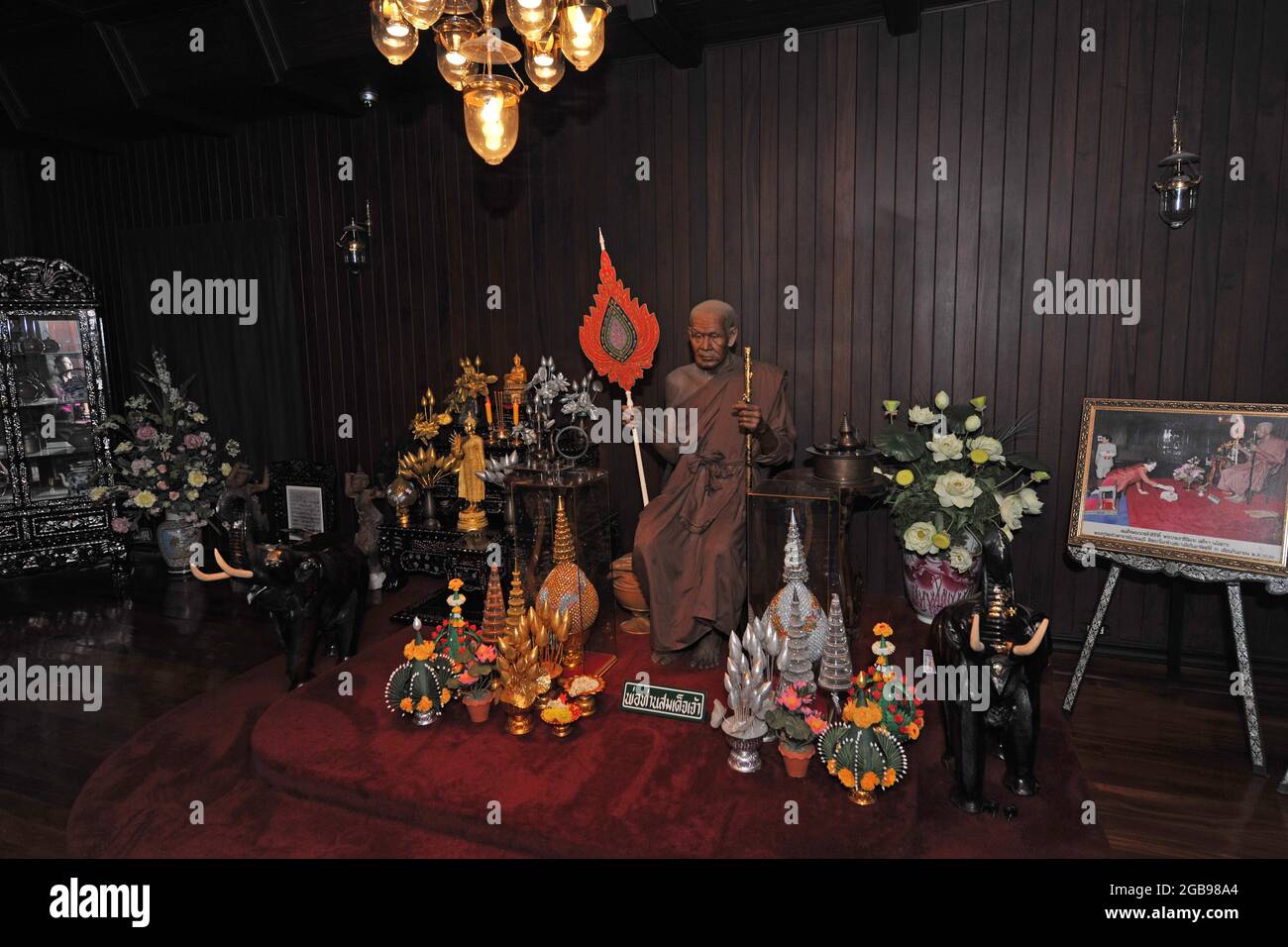 Abgedunkelte Gebetskammer mit Mönchsstatue im buddhistischen Kloster Wat Chalong, Phuket Island, Thailand Stockfoto