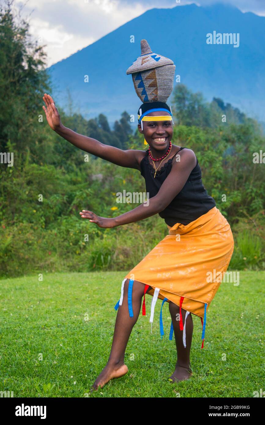 Frau, die einen Korb auf ihrem Hut bei einer Zeremonie ehemaliger Wilderer im Virnicht-Nationalpark in Ruanda, Afrika, trägt Stockfoto