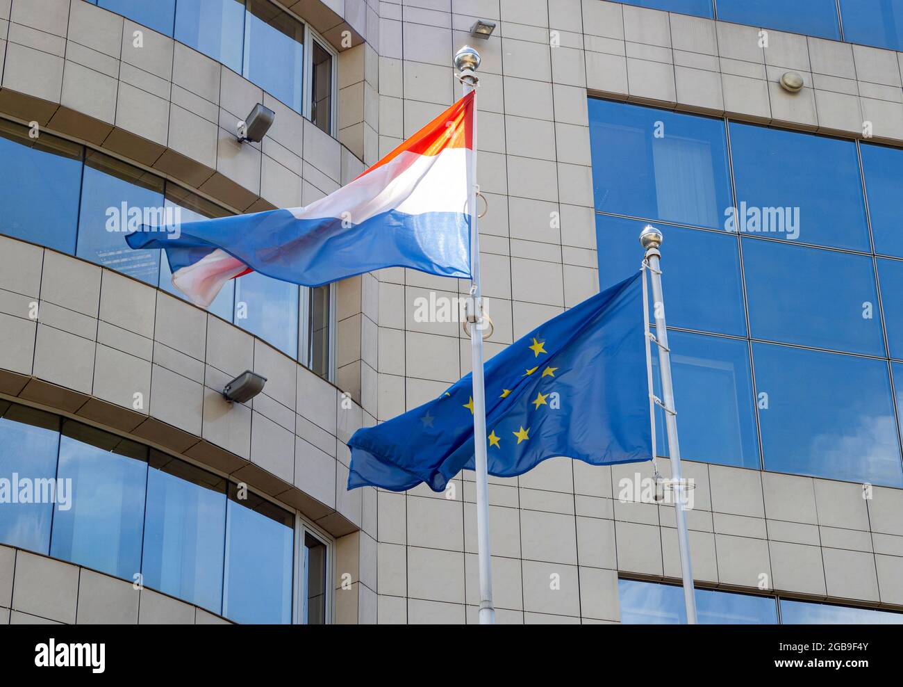 Flaggen der Niederlande und der Europäischen Union auf Fahnenmast winken an windigen Tagen. Flaggen der Niederlande und der EU am Fahnenmast. Stockfoto