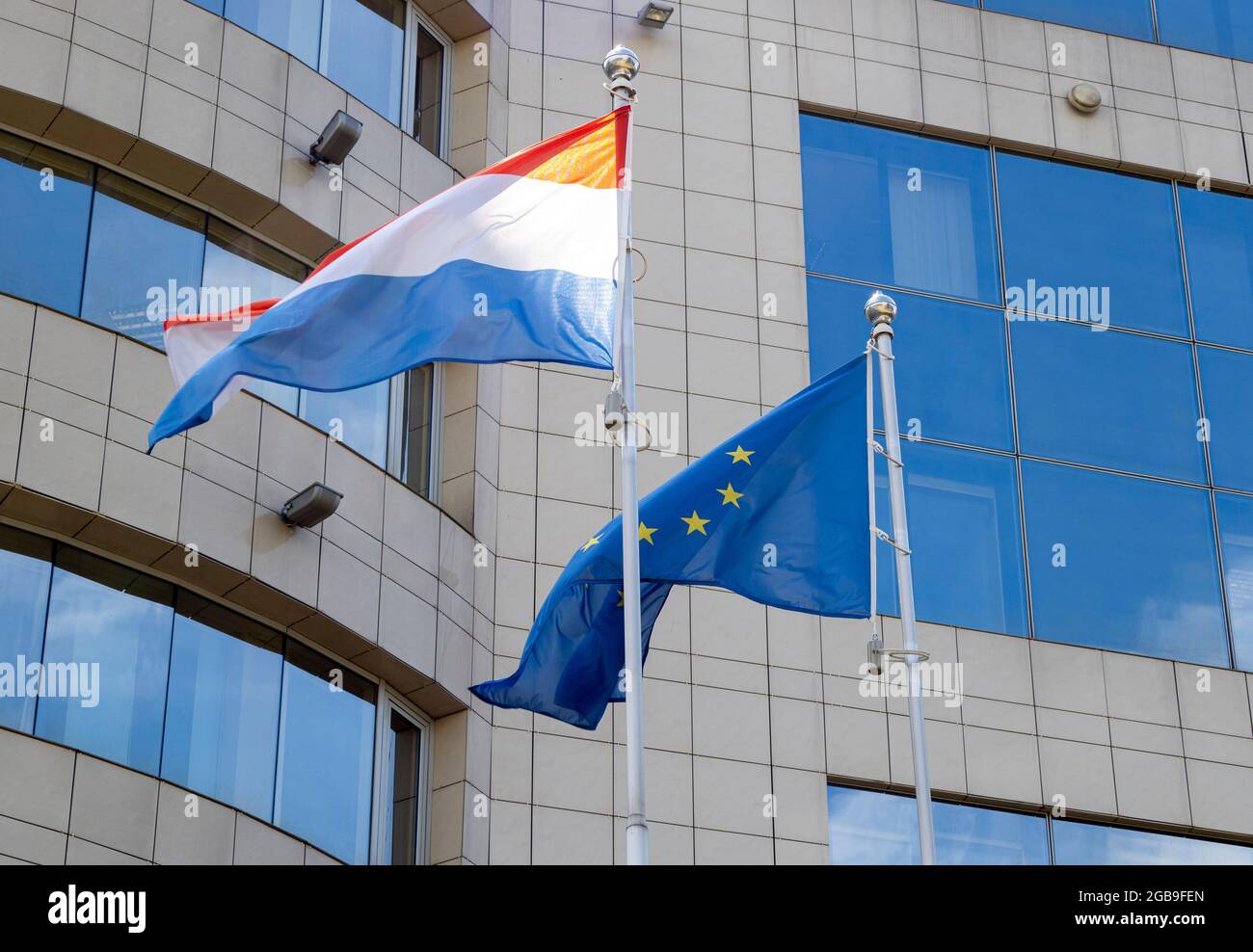 Flaggen der Niederlande und der Europäischen Union auf Fahnenmast winken an windigen Tagen. Flaggen der Niederlande und der EU am Fahnenmast. Stockfoto
