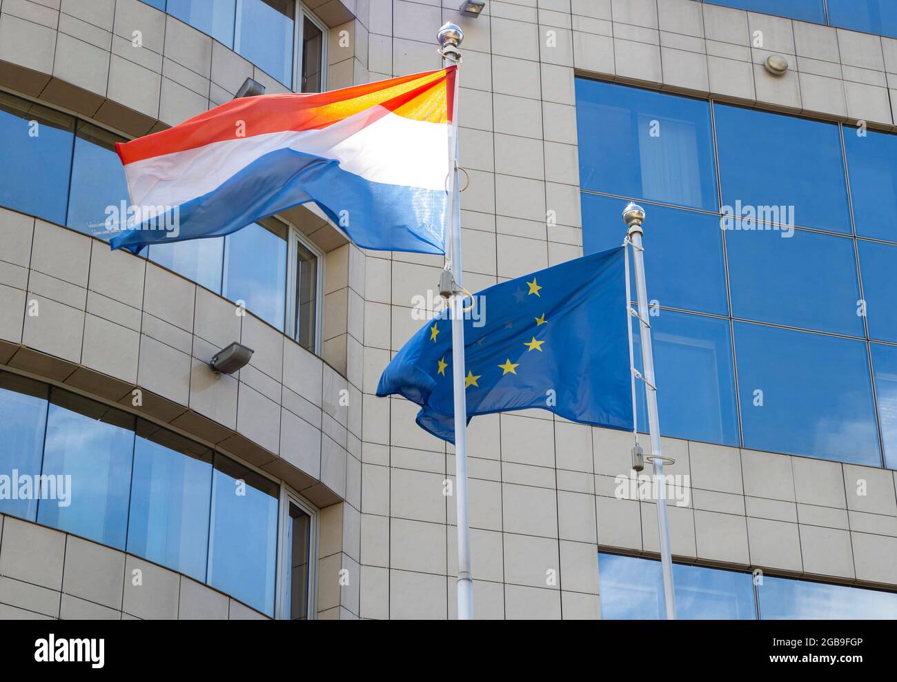 Flaggen der Niederlande und der Europäischen Union auf Fahnenmast winken an windigen Tagen. Flaggen der Niederlande und der EU am Fahnenmast. Stockfoto