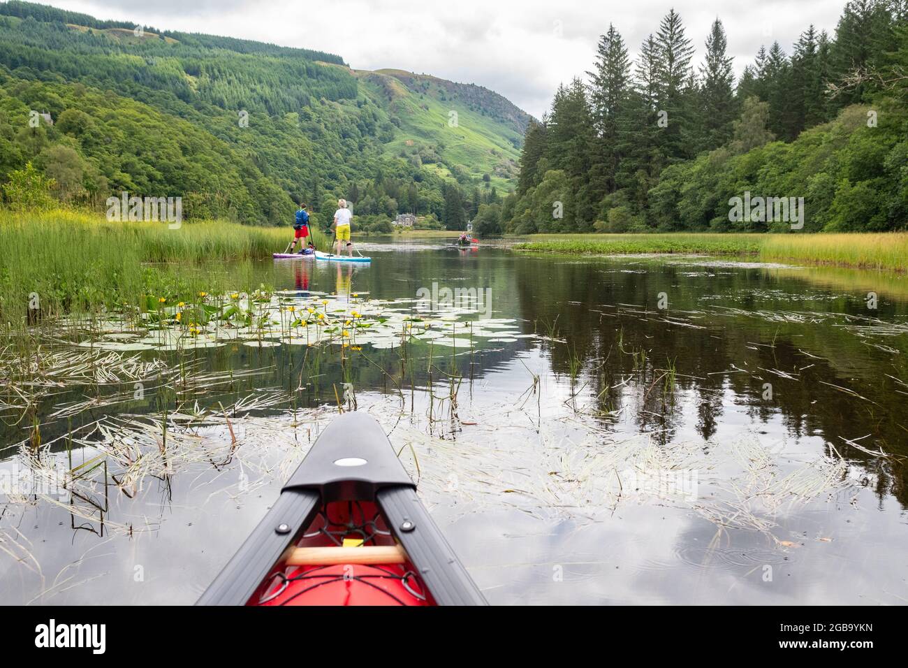 Kanufahrer und Paddelboarder Paddelboarder, die durch die Narrows am Loch ARD, Aberfoyle, den Trossachs, Stirling, Schottland, VEREINIGTES KÖNIGREICH Stockfoto