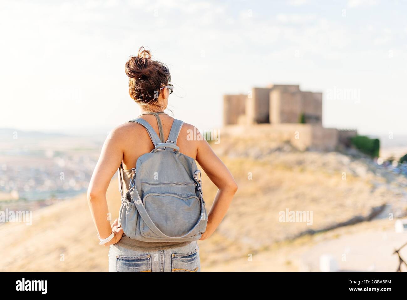 Frau in Sommerkleidung steht und schaut auf eine mittelalterliche Burg Stockfoto