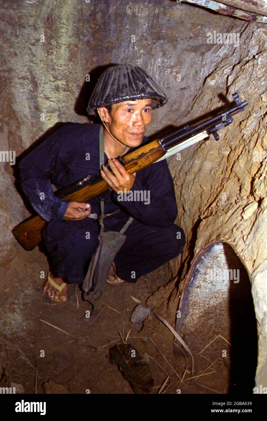 VIETNAM - 1968 - EIN Viet Cong Soldat hockt in einem Bunker / Tunnelsystem an einem nicht identifizierten Ort in Vietnam mit einem SKS Gewehr.während der Vietnam W Stockfoto
