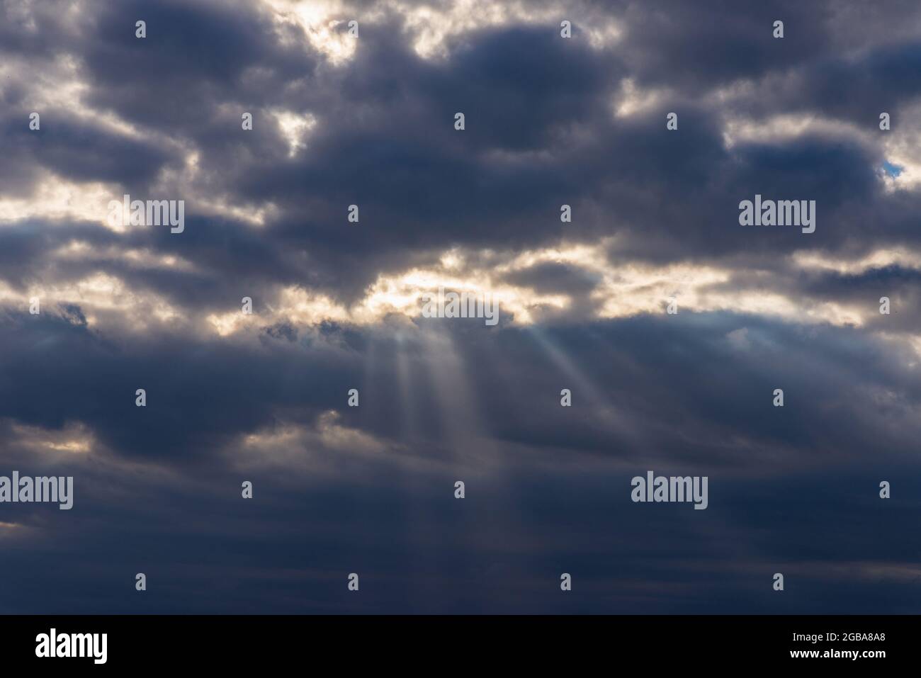 Lichtstrahlen, die durch dunkle Wolken leuchten.schöner dramatischer Himmel mit Sonnenstrahlen.dramatischer Himmel mit Sonnenstrahlen. Stockfoto
