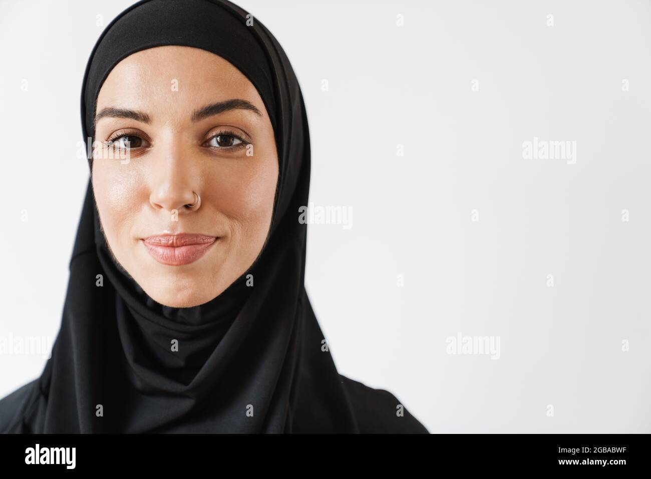 Ein Porträt einer positiven muslimischen Frau mit durchbohrter Nase im weißen Studio Stockfoto
