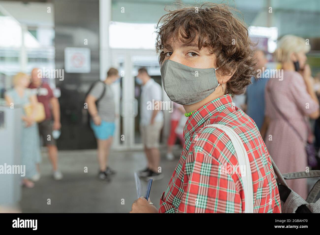 Junge Teenager in einer Schutzmaske mit einem Pass und einem Testergebnis in den Händen Stockfoto