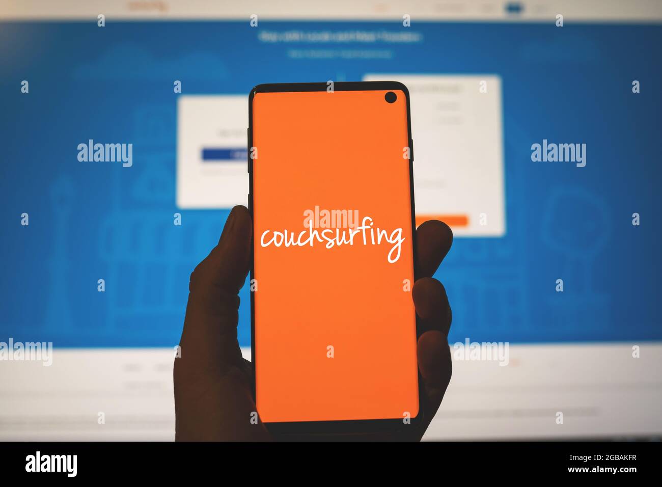 Couchsurfing-Logo auf dem Smartphone in der Hand mit verschwommenem Website-Hintergrund. Hospitality Exchange Service App. Swansea, Großbritannien - 27. Juli 2021. Stockfoto