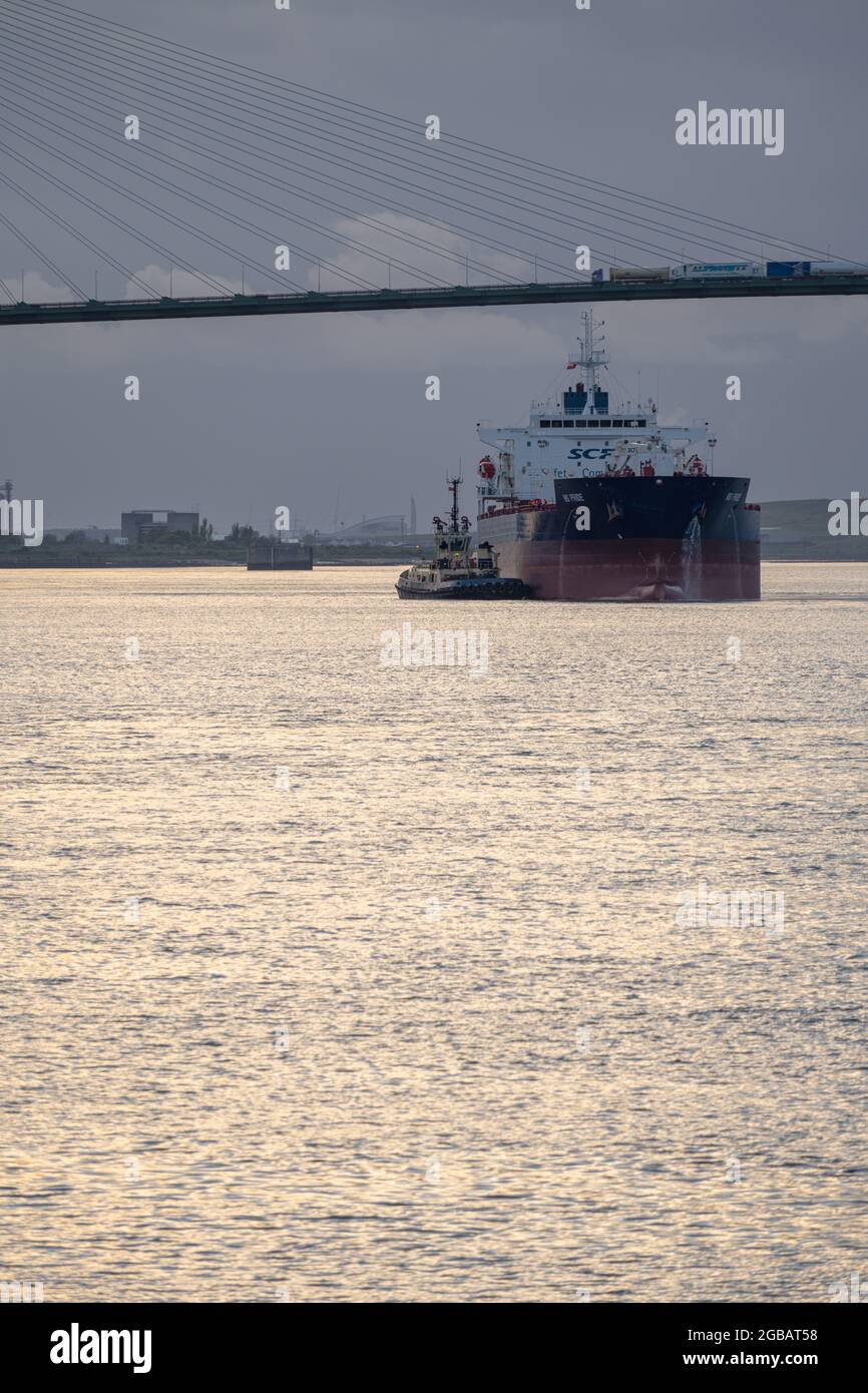 Frachtschiff und Schlepper auf der Themse bei Thurrock mit der Dartford-Brücke dahinter. Stockfoto