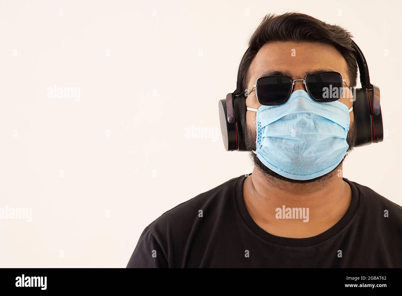 Porträt eines jungen Mannes mit Kopfhörern und Maske im Gesicht. Stockfoto