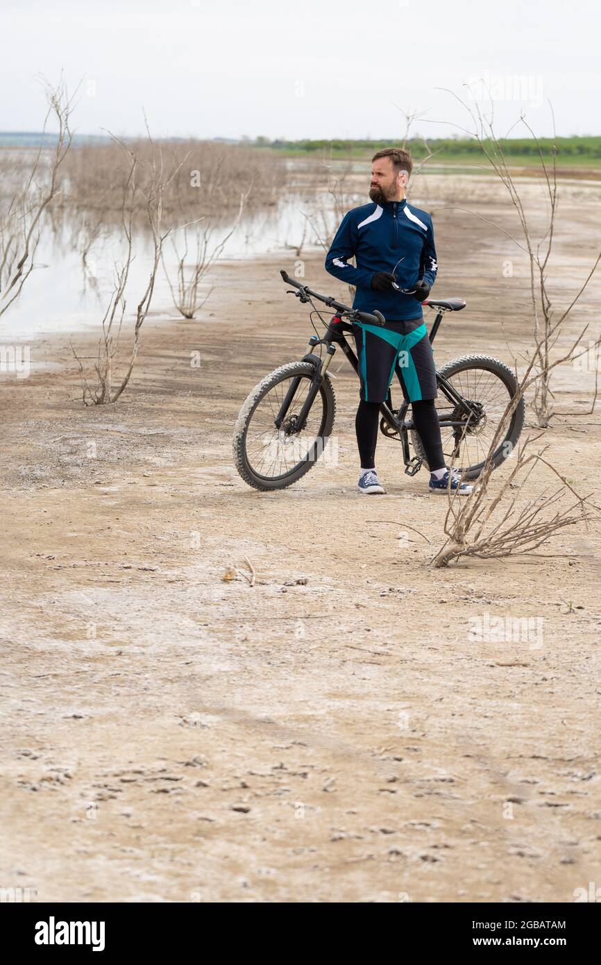 Radfahrer auf einem Mountainbike auf einem Salzstrand auf einem Hintergrund aus Schilf und einem See Stockfoto