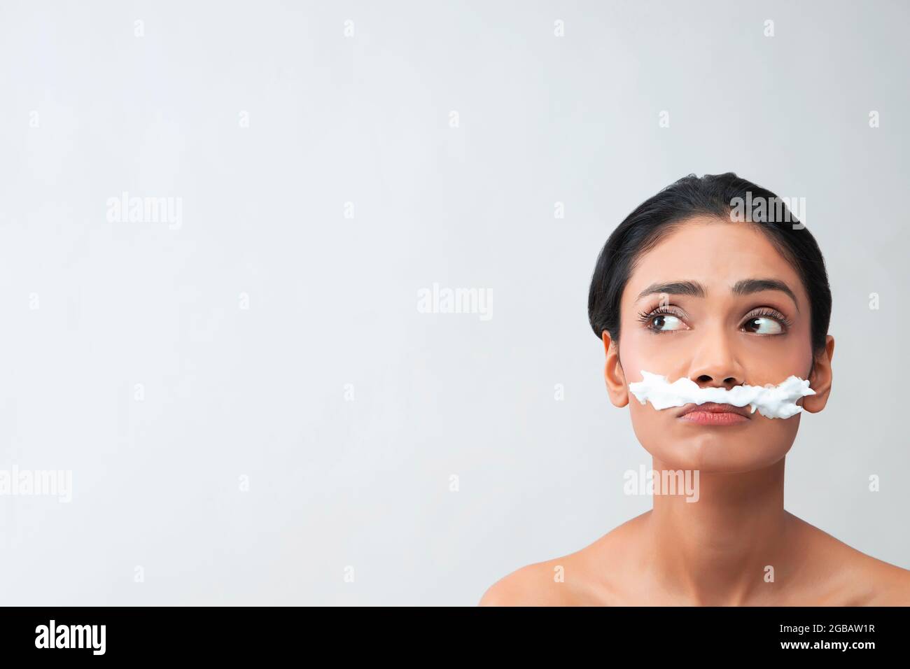 Eine junge Frau mit Haarentfernungscreme auf ihrem Gesicht, um Gesichtsbehaarung zu entfernen. Stockfoto
