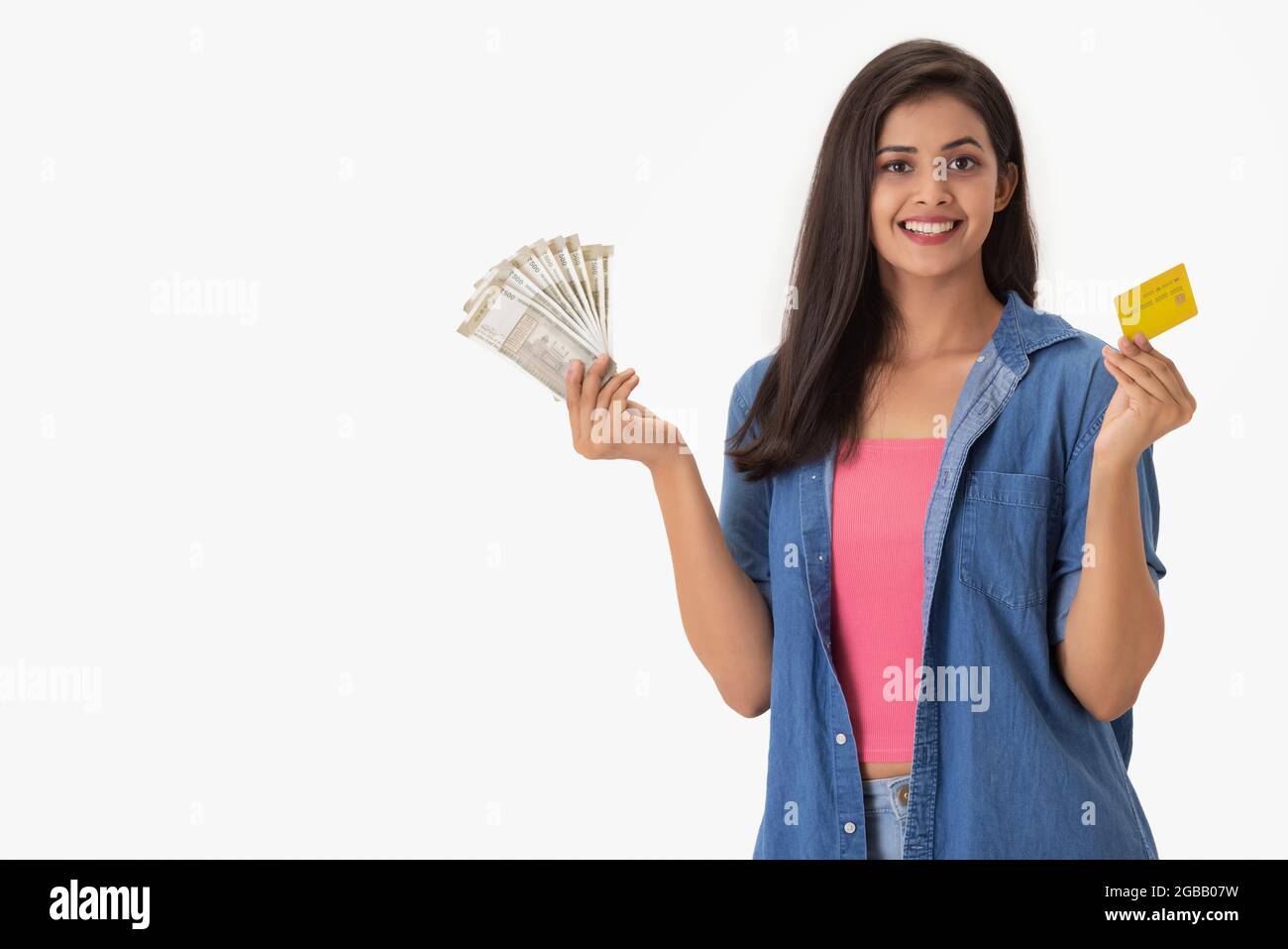 Eine junge Frau mit Kreditkarte und Bargeld in jeder Hand. Stockfoto