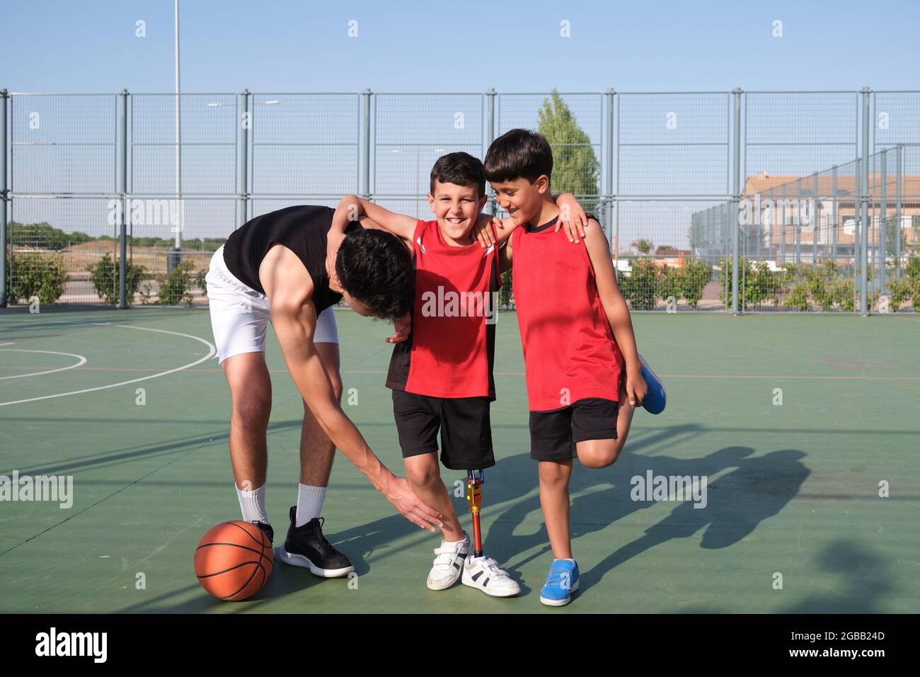 Zwei Brüder helfen ihrem Bruder mit einer Beinprothese, um sein Bein zu strecken. Stockfoto