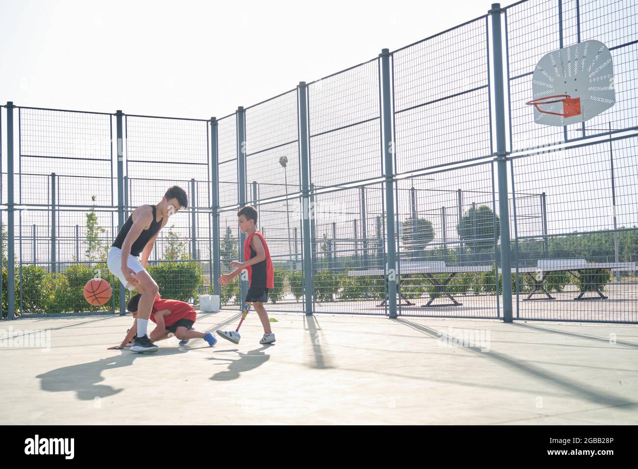 Drei Brüder spielen Basketball, einer von ihnen hat eine Beinprothese. Stockfoto