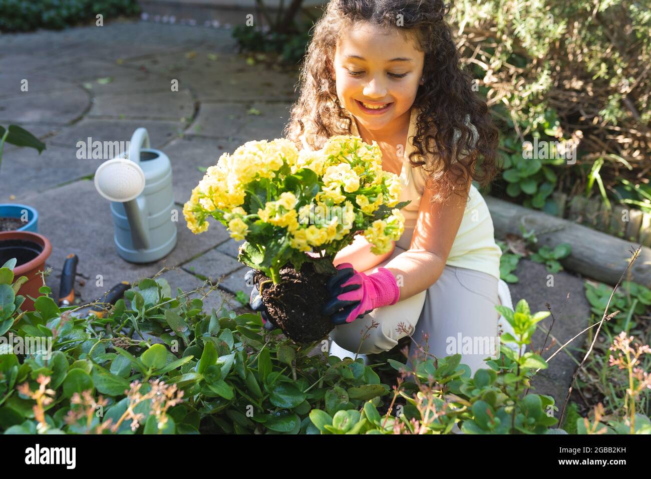 Lächelndes Mädchen mit gemischter Rasse, das Blumen im Hinterhof pflanzt Stockfoto