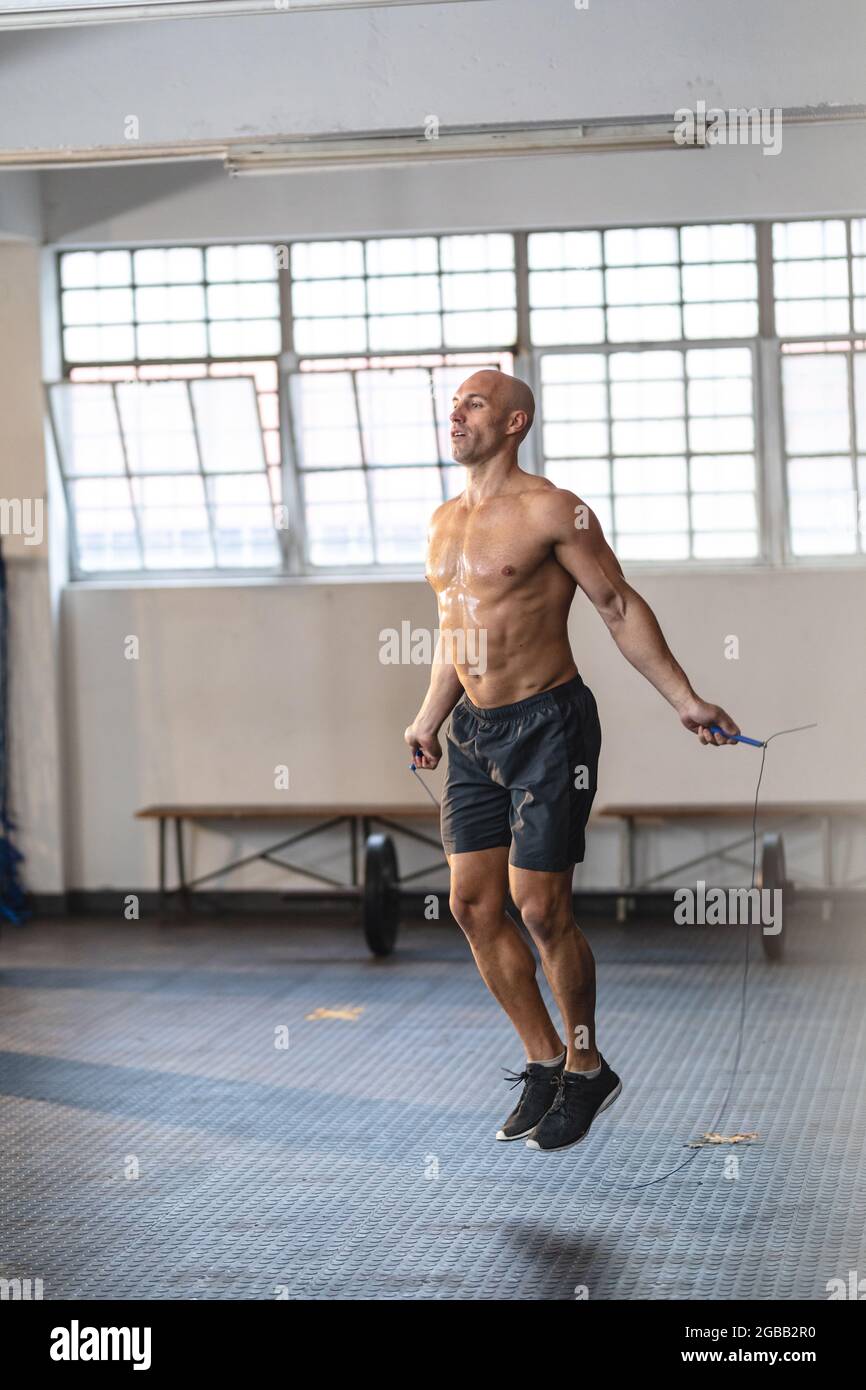 Starker kaukasischer Mann, der im Fitnessstudio trainiert, Seil hält und springt Stockfoto