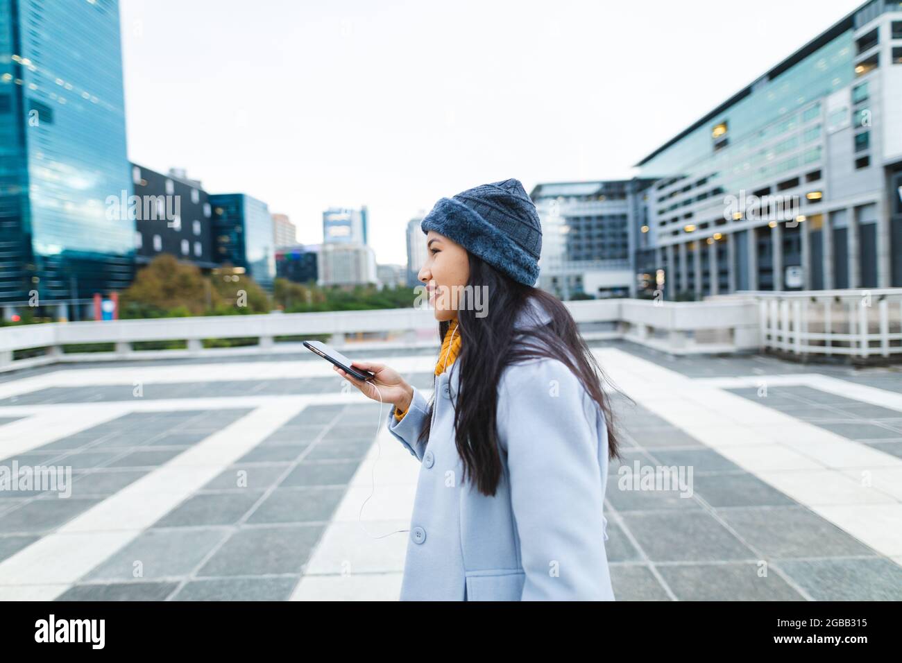 Asiatische Frau lächelt und benutzt Smartphone auf der Straße Stockfoto