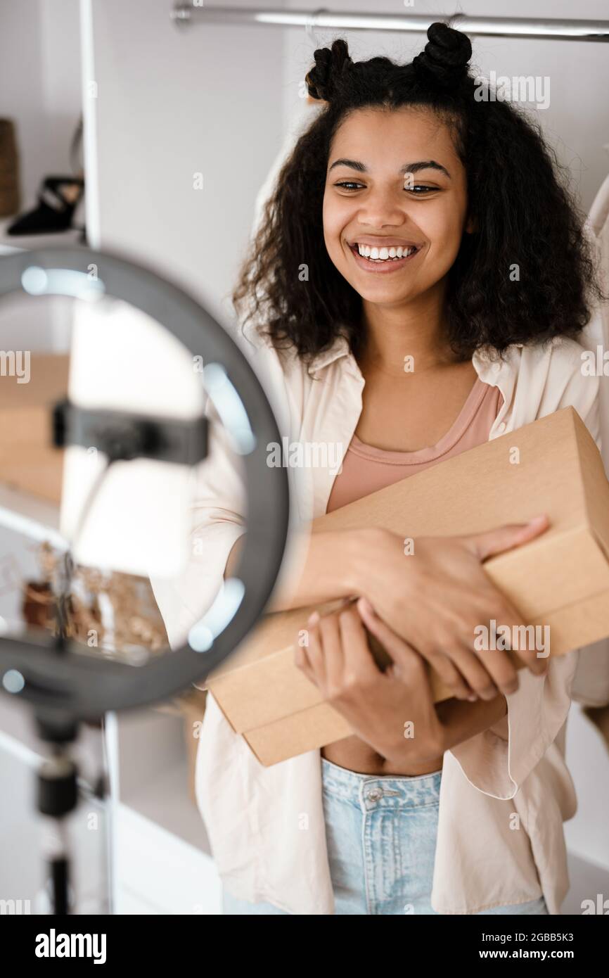 Glückliche junge afrikanische Frau Influencer Auspacken Paket vor einer  Kamera zu Hause stehen Stockfotografie - Alamy