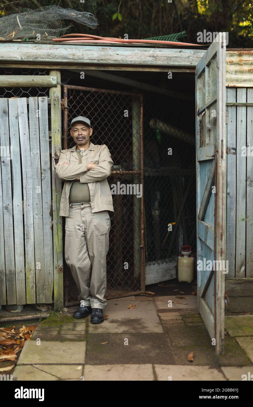 afroamerikanischer Gärtner mit gekreuzten Händen und Blick auf die Kamera im Gartencenter Stockfoto