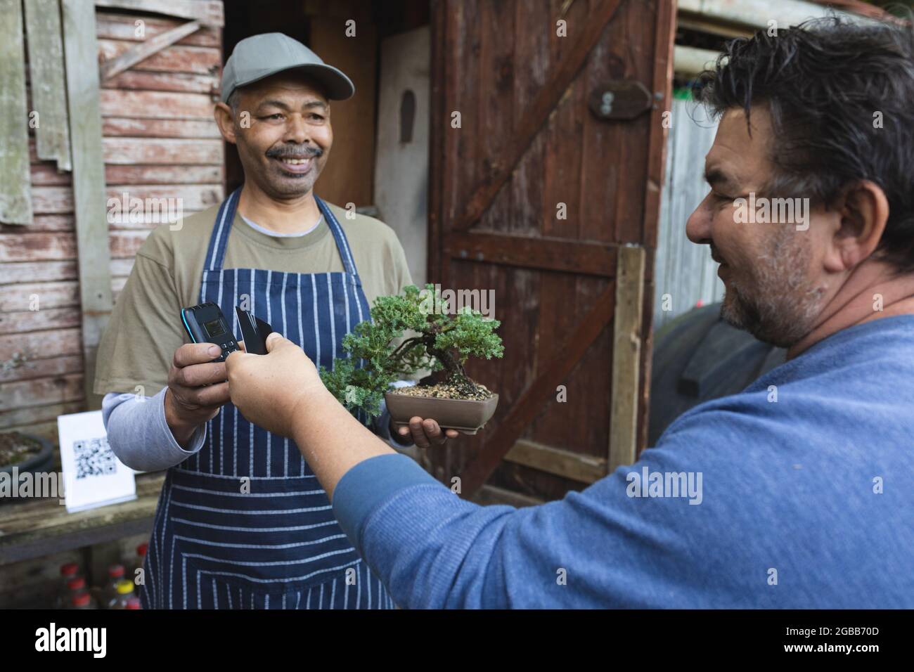 Zwei verschiedene Männer nutzen kontaktlose Zahlungen im Gartencenter Stockfoto