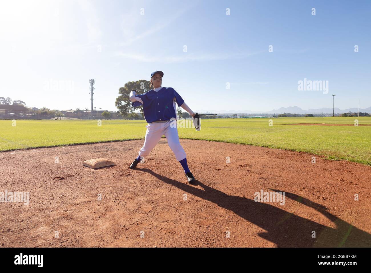 Gemischtes Rennen weibliche Baseballspielerin auf sonnigen Baseballfeld werfen Ball während des Spiels Stockfoto