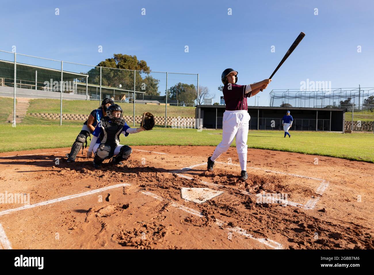 Verschiedene Baseballspielerinnen in Aktion auf sonnigem Baseballfeld während des Spiels Stockfoto