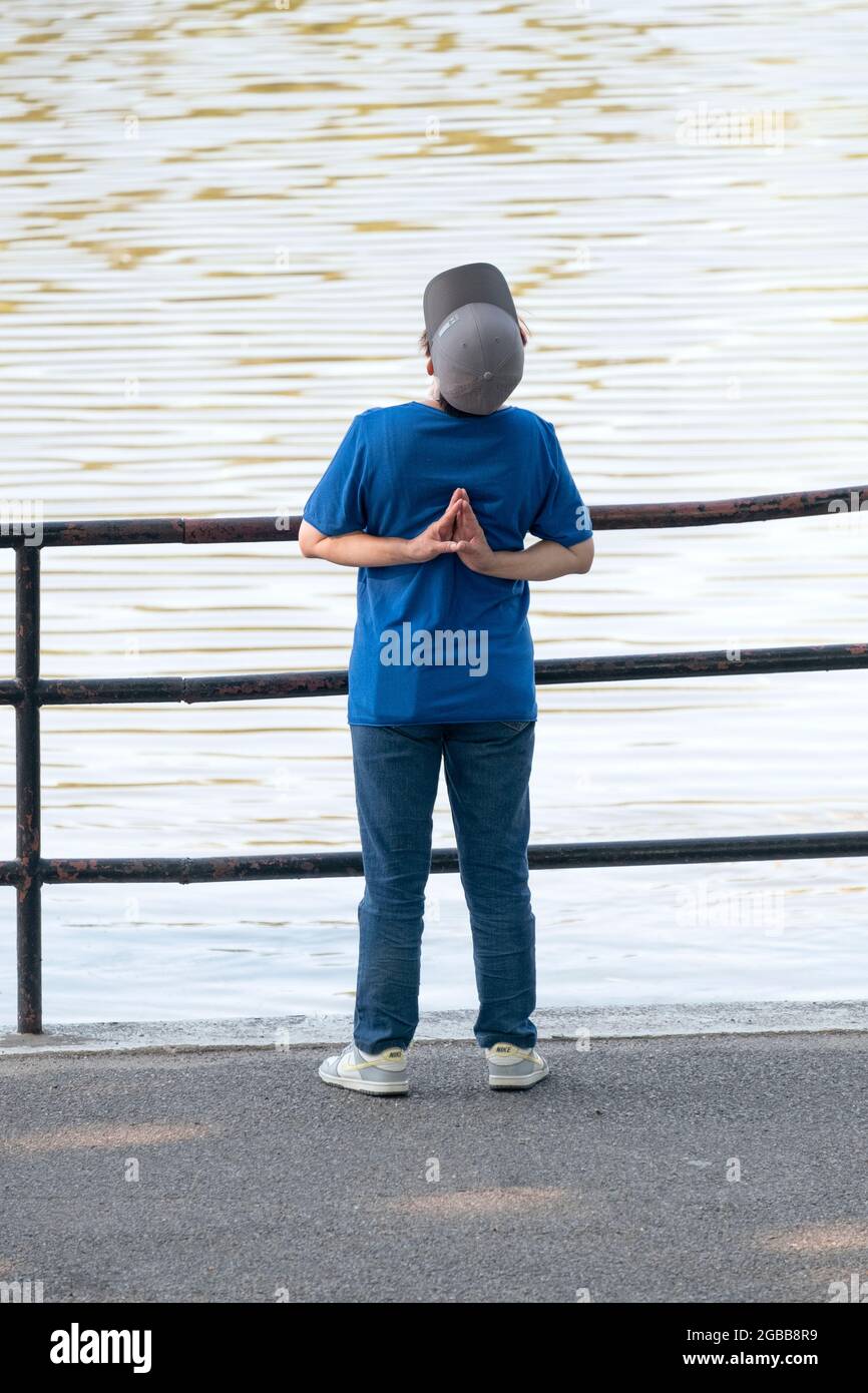 Eine Frau mit flexibler Passform streckt ihre Schulter- und Rückenmuskulatur vor dem Training in einem Park in Flushing, Queens, New York City. Stockfoto