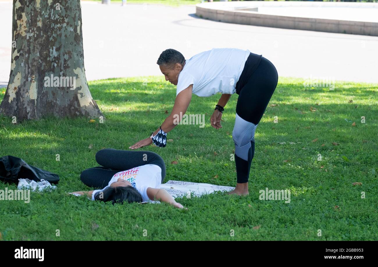 Ein Yoga- und Wellnesslehrer mittleren Alters, der einen Schüler in einer Klasse im Flushing Meadows Corona Park in Queens, New York City, unterrichtet. Stockfoto