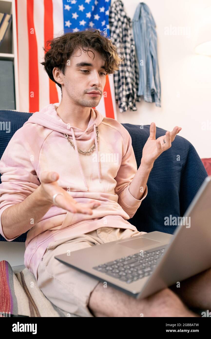 Ein moderner Teenager diskutiert mit einem Klassenkameraden im Videochat vor dem Laptop über Hausaufgaben Stockfoto