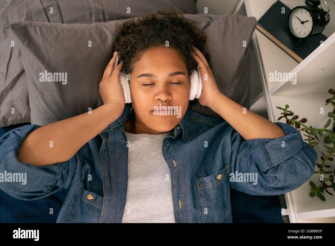 Teenager-Mädchen im Bett liegen und hören Entspannungsmusik vor dem Schlaf Stockfoto