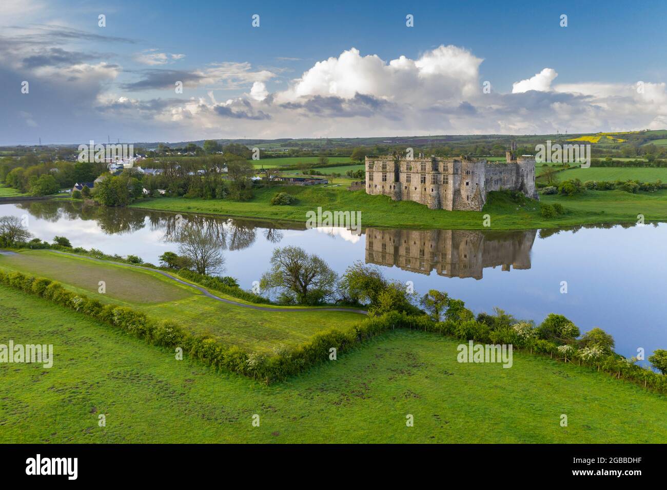 Carew Castle spiegelte sich an einem ruhigen Frühlingsmorgen im Mühlenteich, im Pembrokeshire Coast National Park, Wales, Großbritannien, Europa Stockfoto