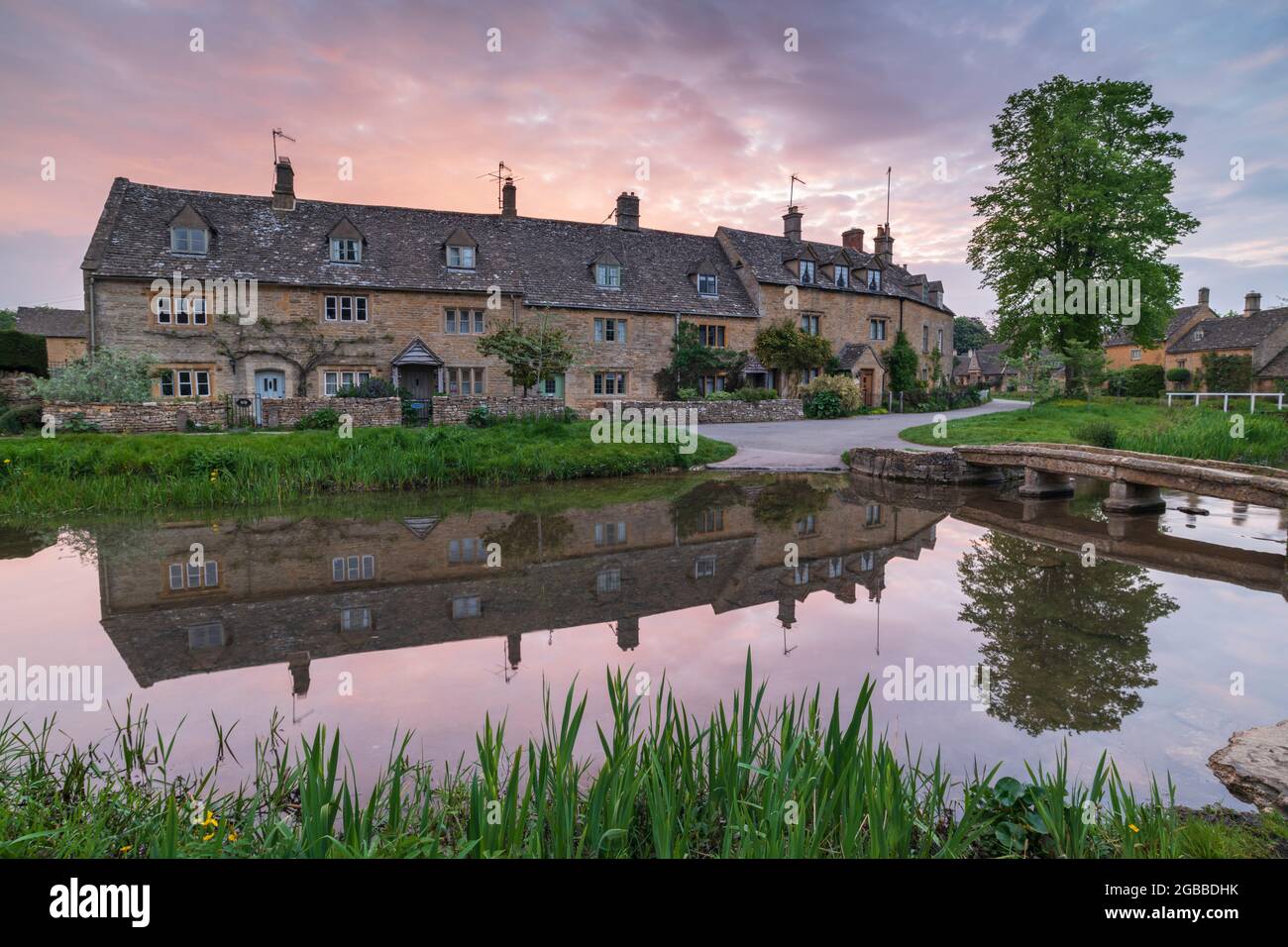 Hübsche Cotswolds-Cottages spiegeln sich in der Dämmerung im Frühjahr im Dorf Lower Slaughter, Gloucestershire, England, Großbritannien, im River Eye wider Stockfoto