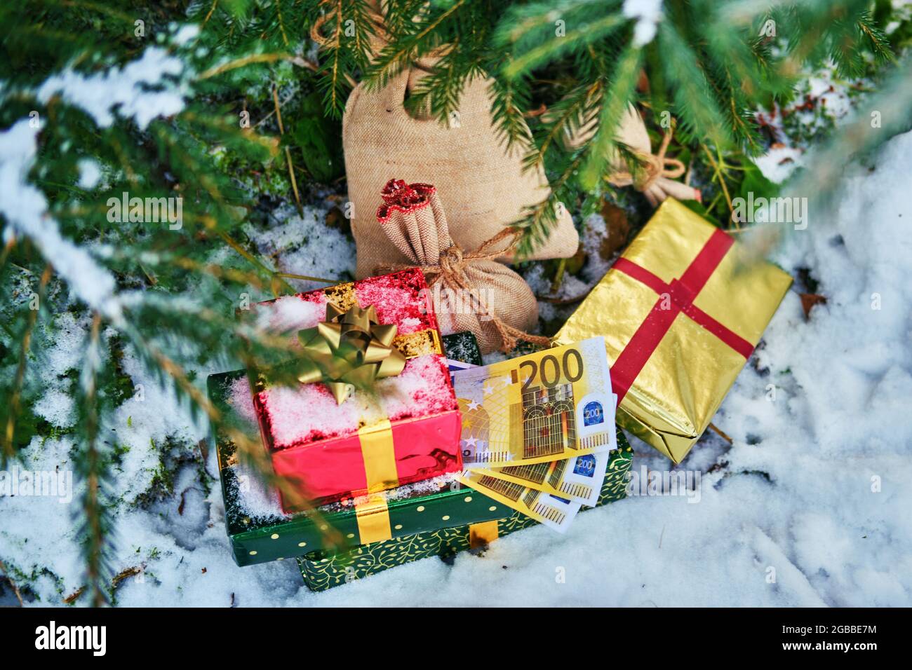 Geschenke in roten Schachteln und Geld in Euro liegen im neuen Jahr unter dem Weihnachtsbaum Stockfoto