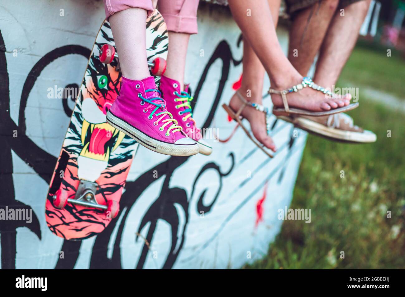 Nahaufnahme von Teenagerbeinen mit rosa Sneakern und Skateboard Stockfoto