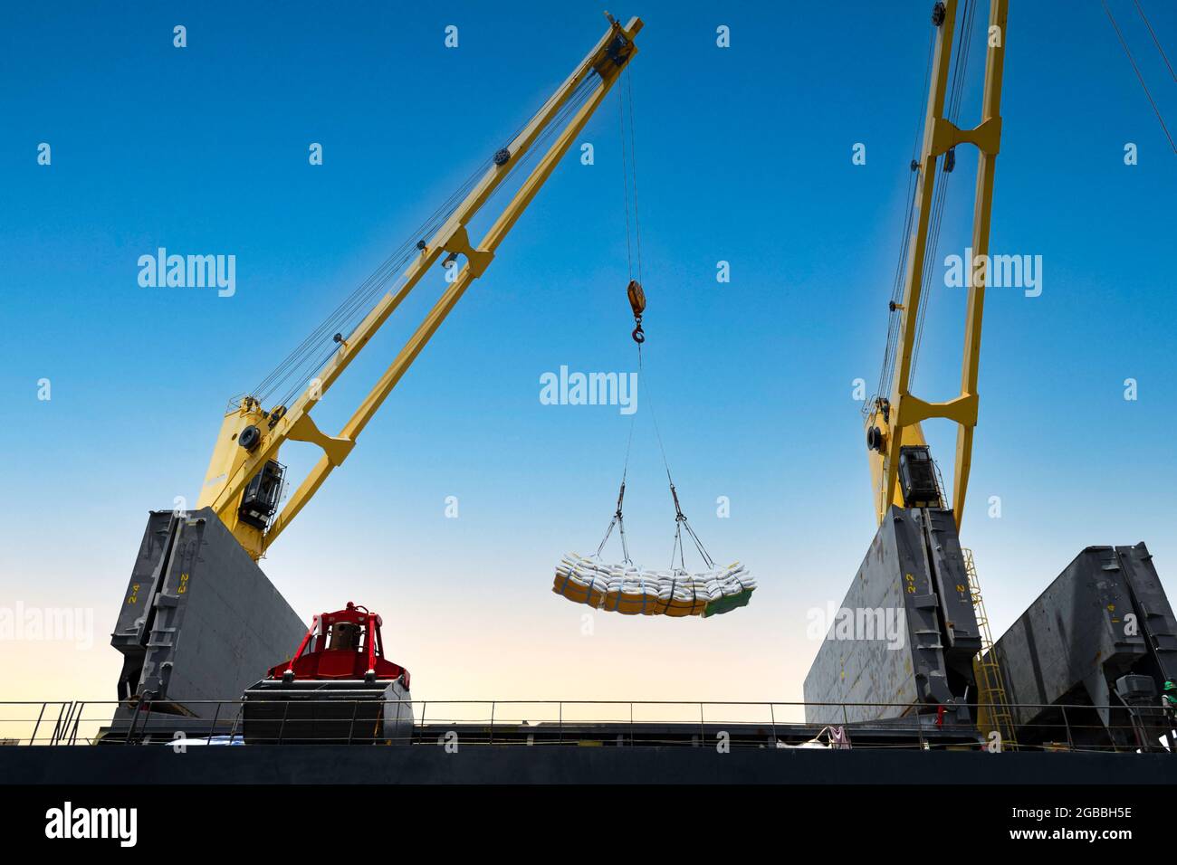 Schiffskran hebt die Jumbo-Schlinge der Zuckersäcke in den Frachtraum des Schiffes. Bag Fracht Verladung zu Schiff für den Export. Stockfoto