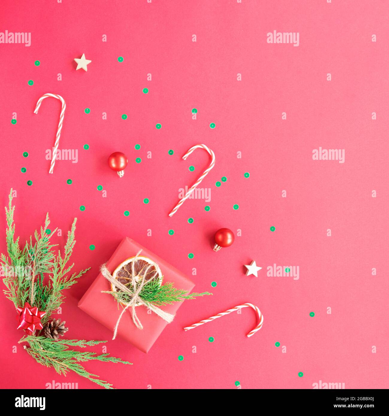 Hintergrund zu Weihnachten und Neujahr. Geschenkboxen mit Konfetti, Kugeln und Kugeln auf rotem Hintergrund. Draufsicht, flach liegend, Kopierbereich. Stockfoto