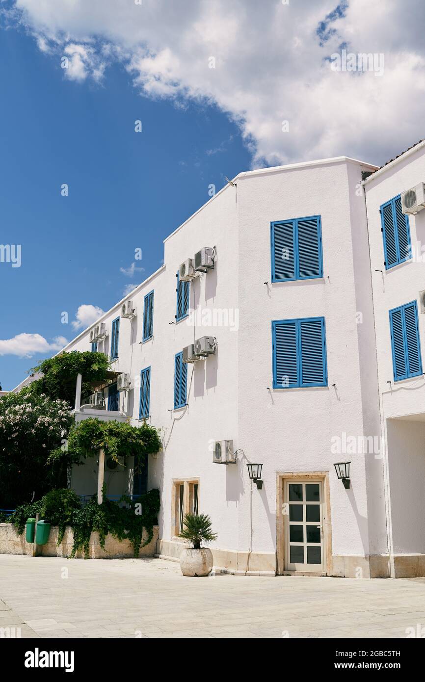 Dreistöckiges weißes Apartmentgebäude mit viel Grün Stockfoto