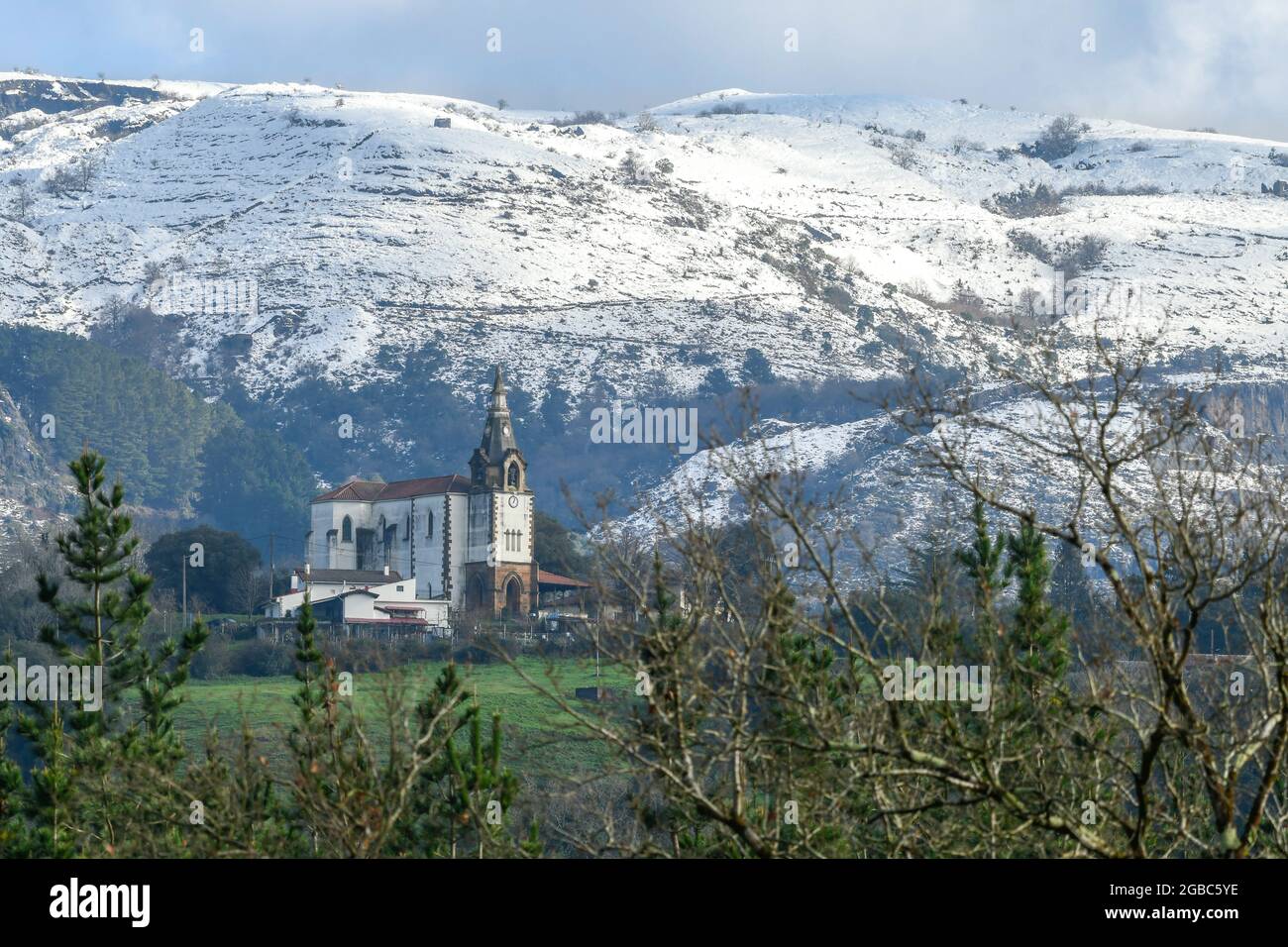Kirche von San Esteban de Galdames mit den verschneiten Bergen im Hintergrund Stockfoto