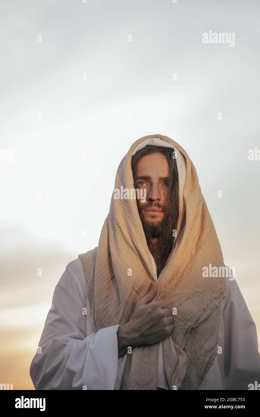 Jesus Christus steht in seiner traditionellen weißen Robe vor dem Hintergrund des Himmels. Hochformat. Stockfoto