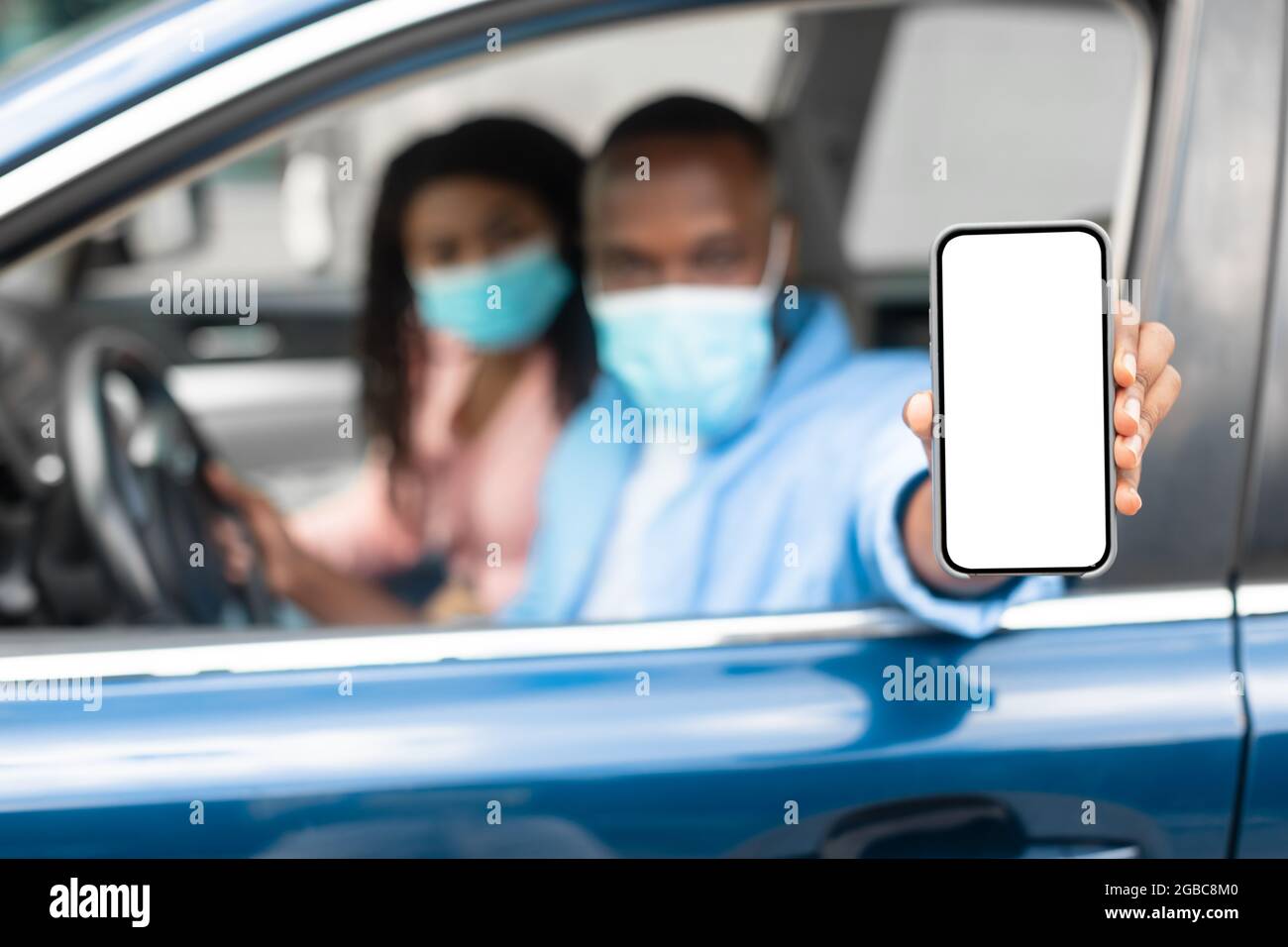 Fahrer in Maske mit Anzeige Smartphone mit leerem Bildschirm Stockfoto