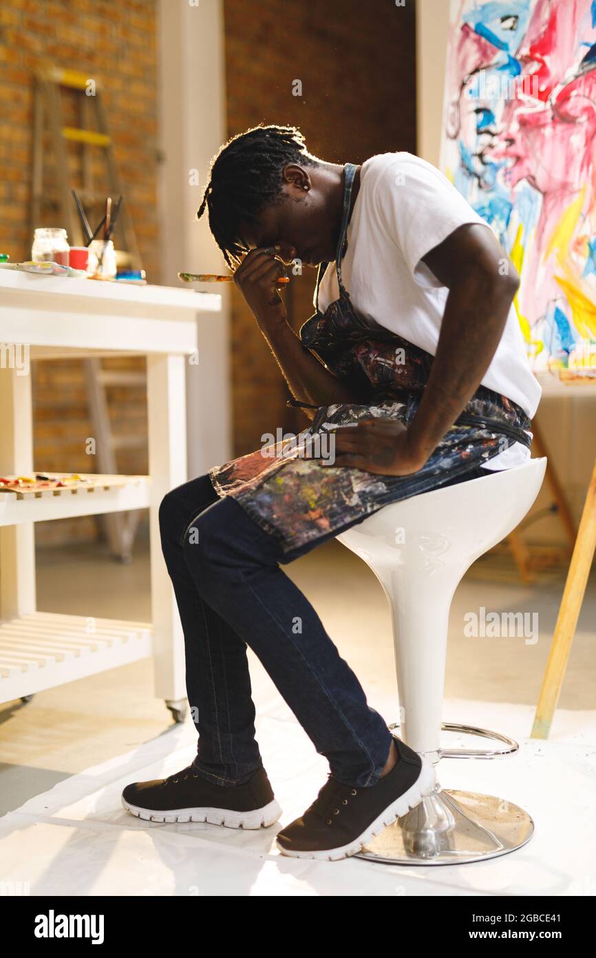 Müde afroamerikanische Malerin bei der Arbeit im Kunststudio Stockfoto