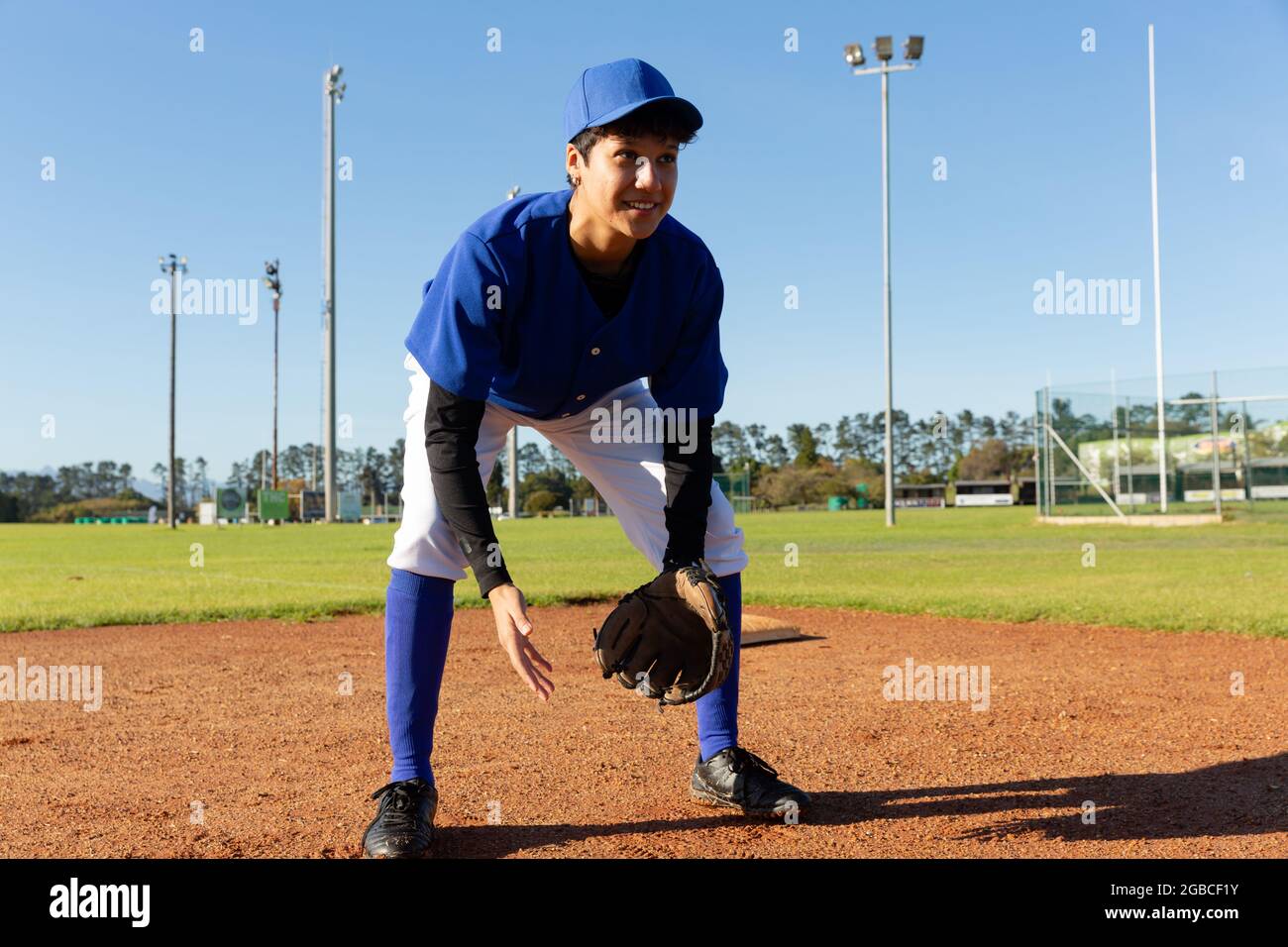 Mixed Race weibliche Baseballkrug stehen auf sonnigen Baseballfeld lächelnd während des Spiels Stockfoto